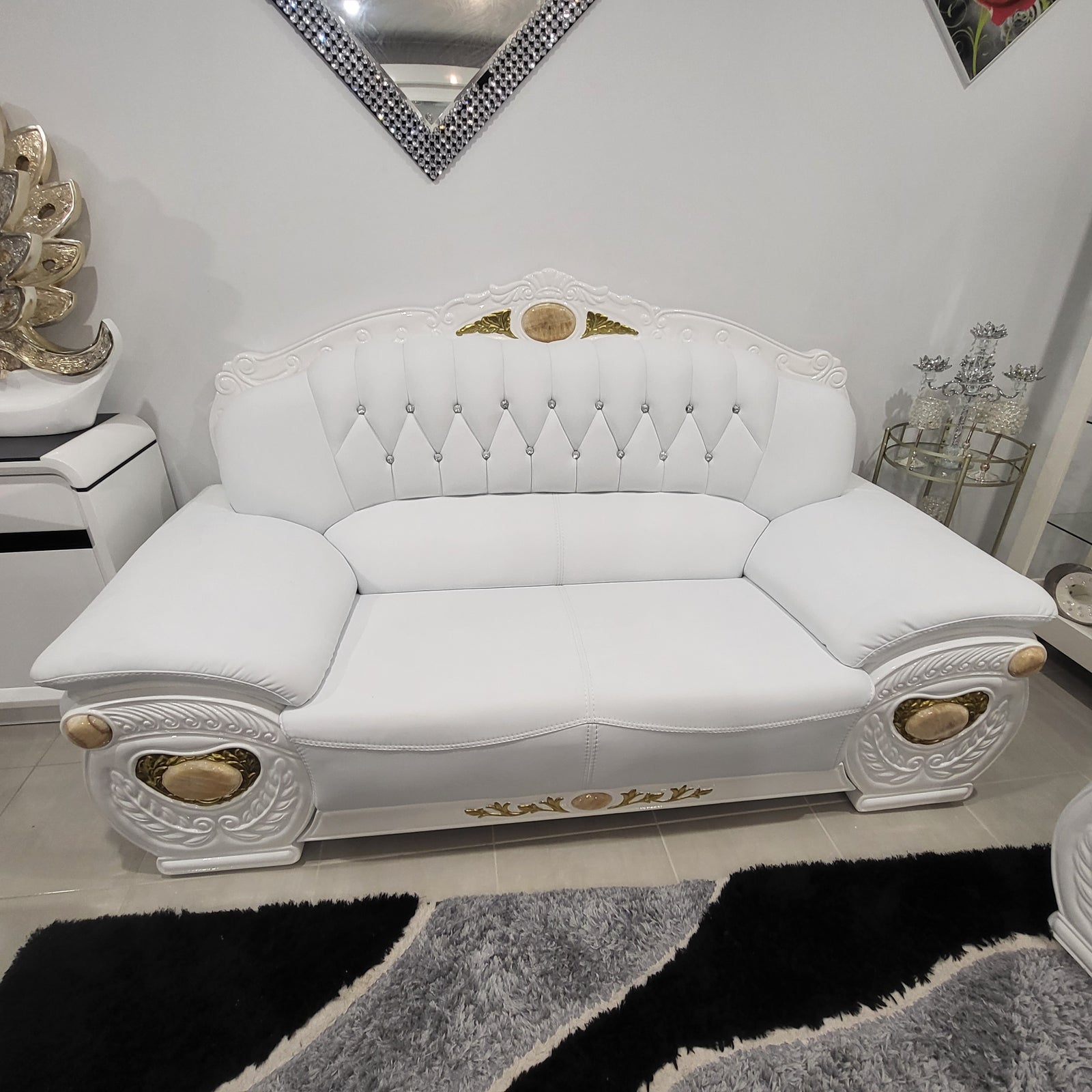 Decorative white headboard with gold accents on a bed in a bedroom setting.