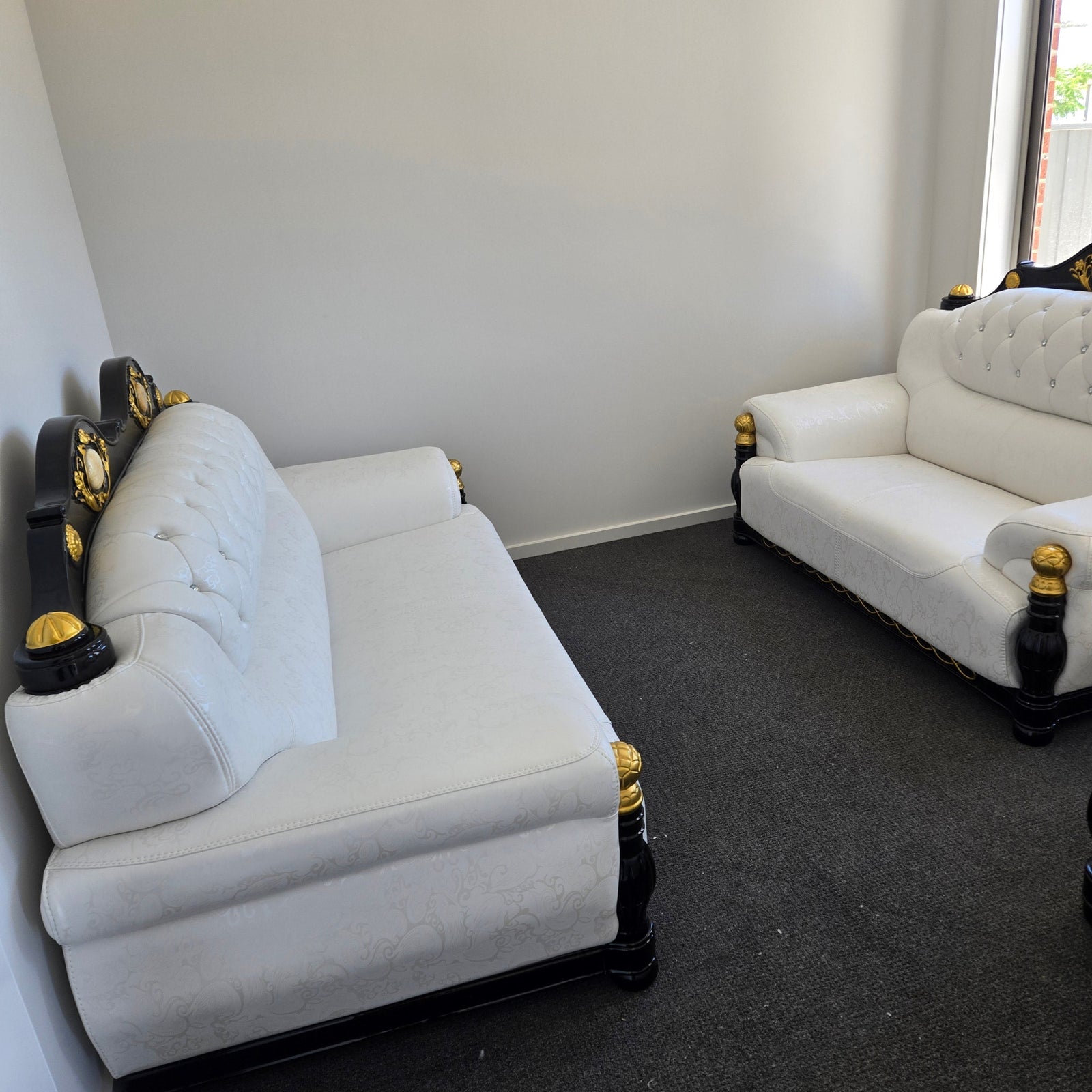 White upholstered car seats with gold accents on a black surface.