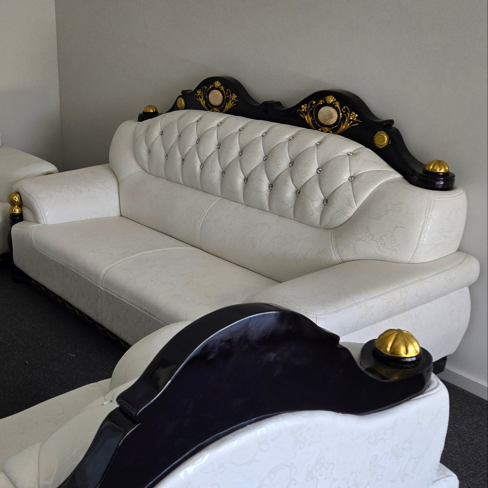 A set of cream leather sofas with black wood frames and gold accents, including a three-seater, two-seater, and a single-seater sofa.