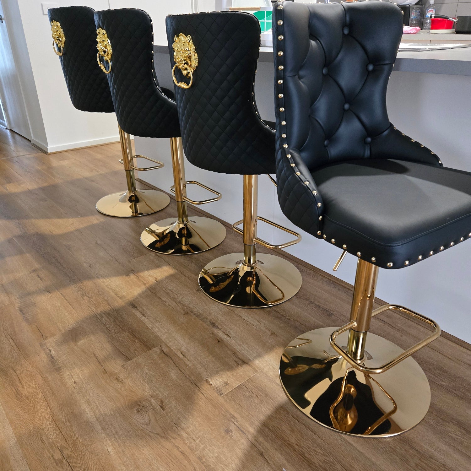 Black bar stools with gold legs on a wooden floor