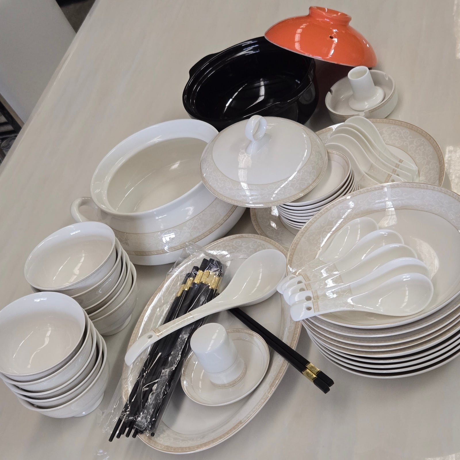 Collection of white ceramic dishes and cutlery on a white surface