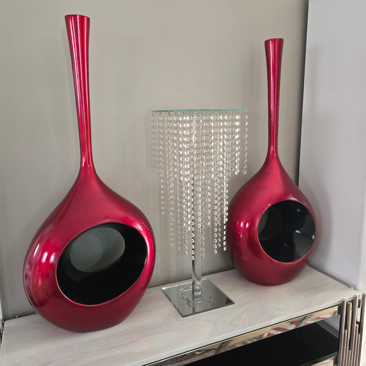 Two red ceramic pots with long handles on a light surface.