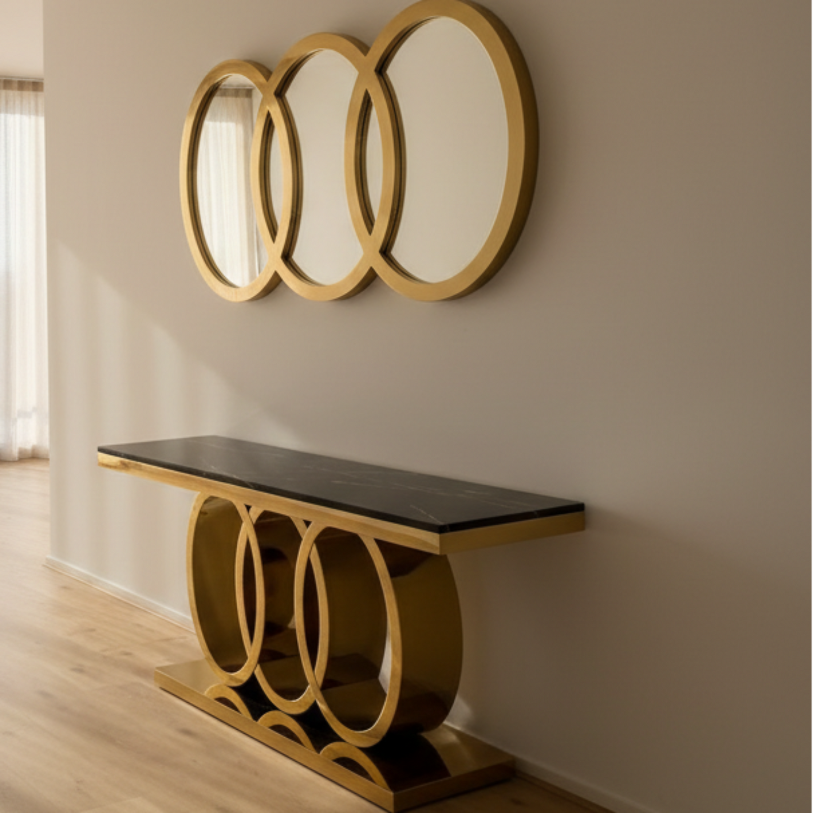 Decorative console table with gold base and black marble top in front of a wall with three round gold mirrors.