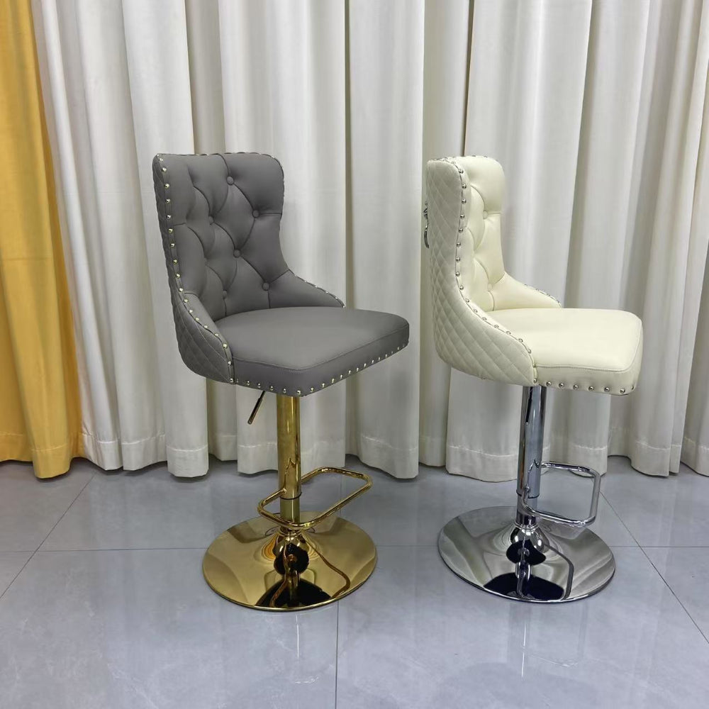 Two bar stools, one grey and one white, with gold and silver bases against a curtain backdrop.