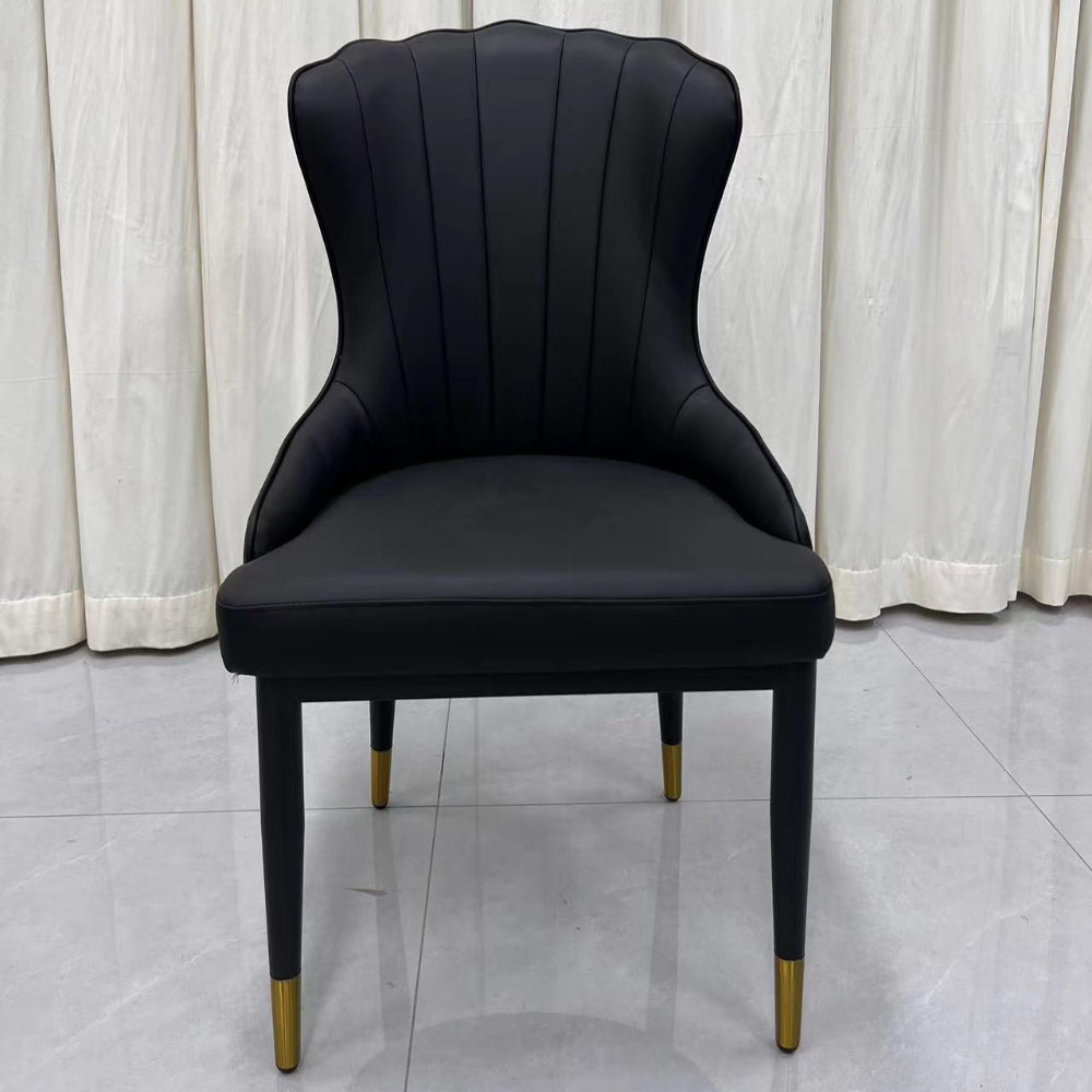 Black upholstered chair with gold legs on a light gray floor and white curtain background