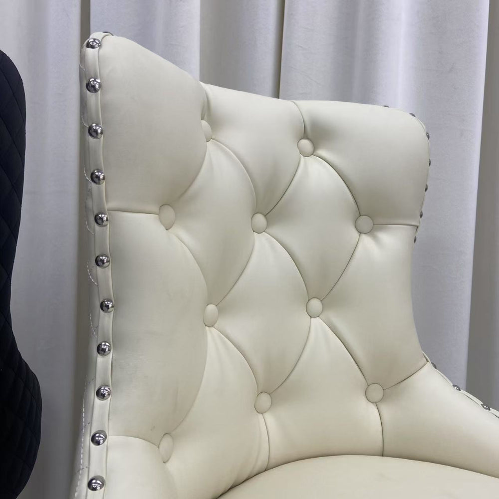 White tufted chair with decorative studs against a white curtain background