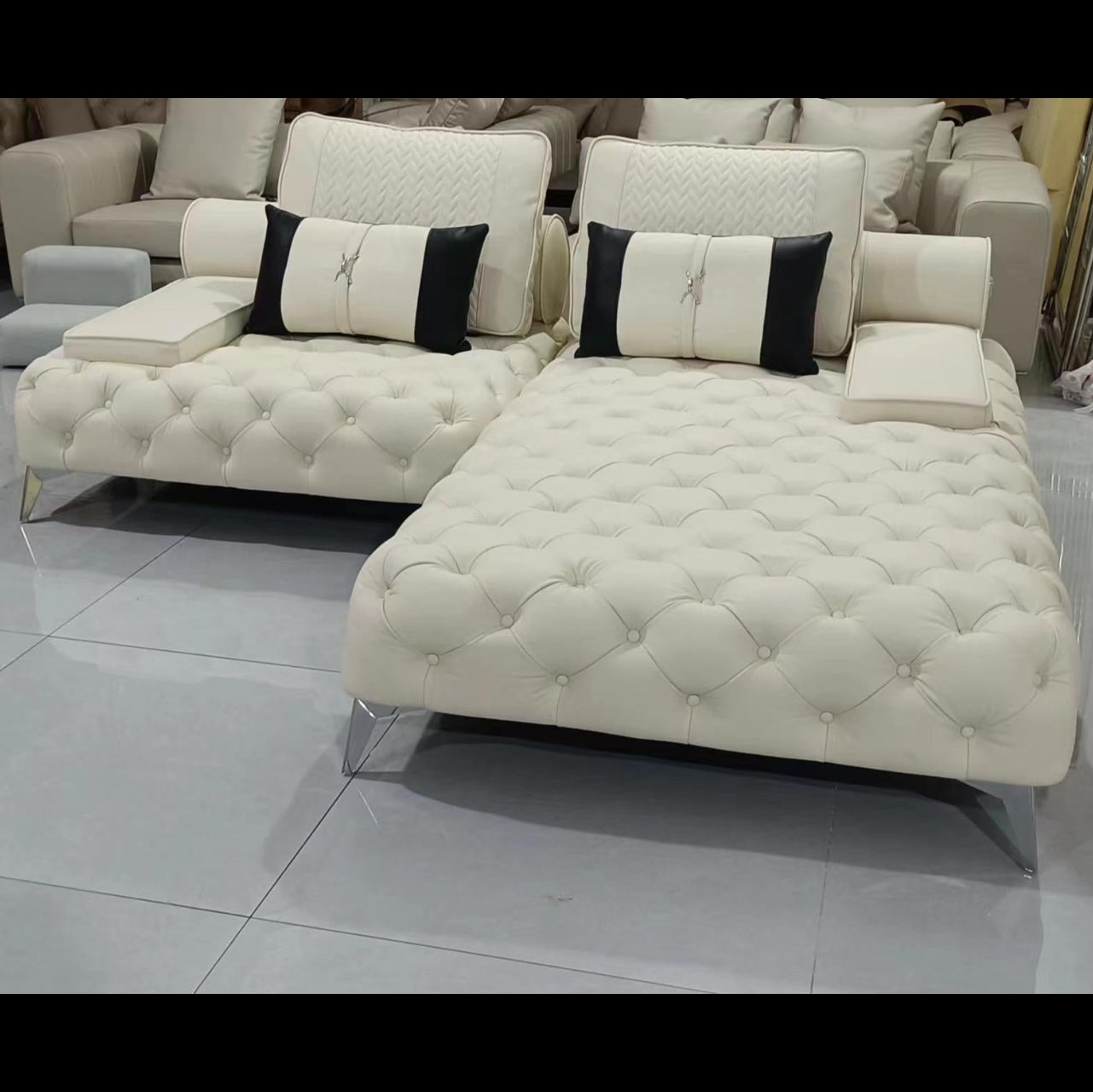 White tufted sofa with black and white cushions on a tiled floor.