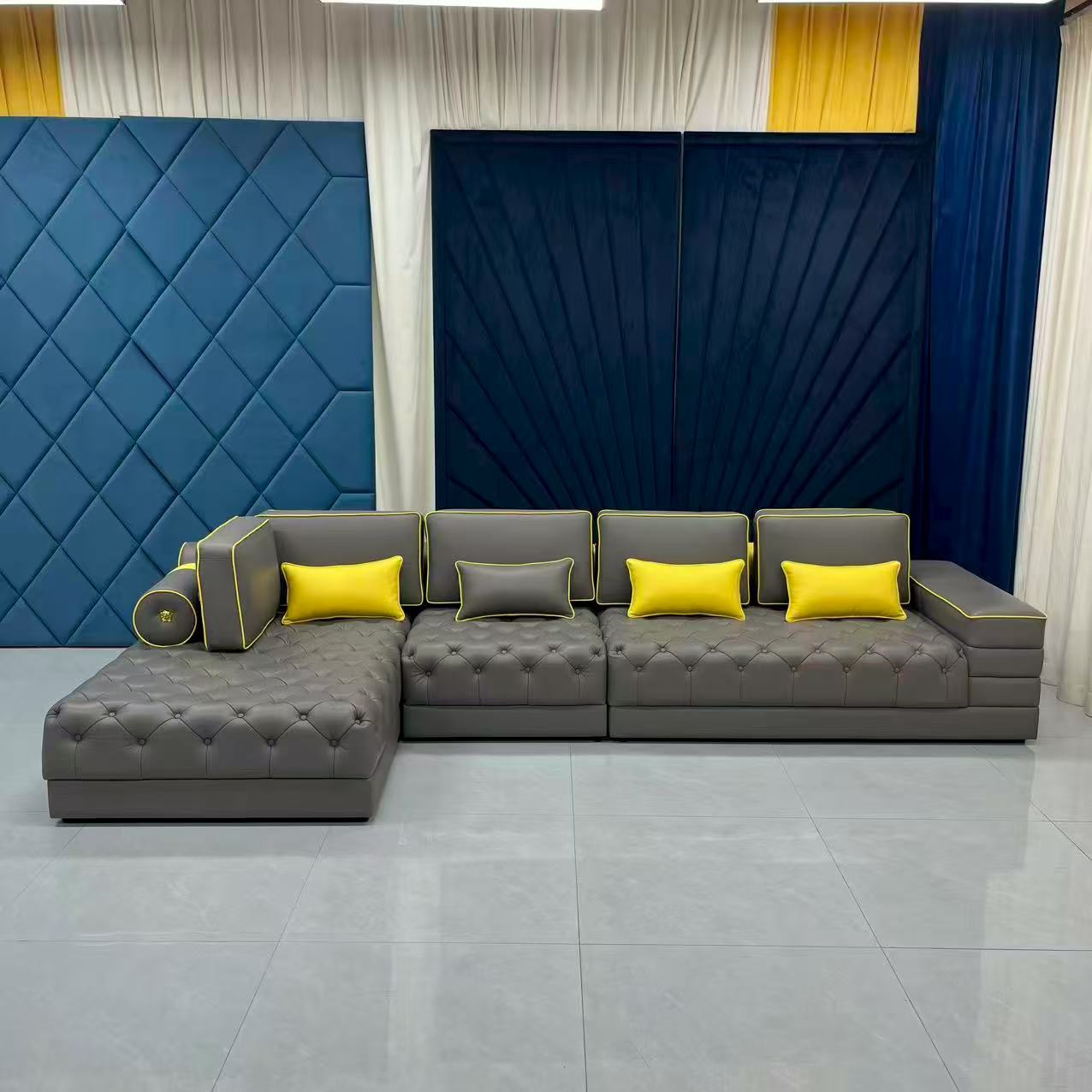 Gray sectional sofa with yellow cushions against a modern wall design.