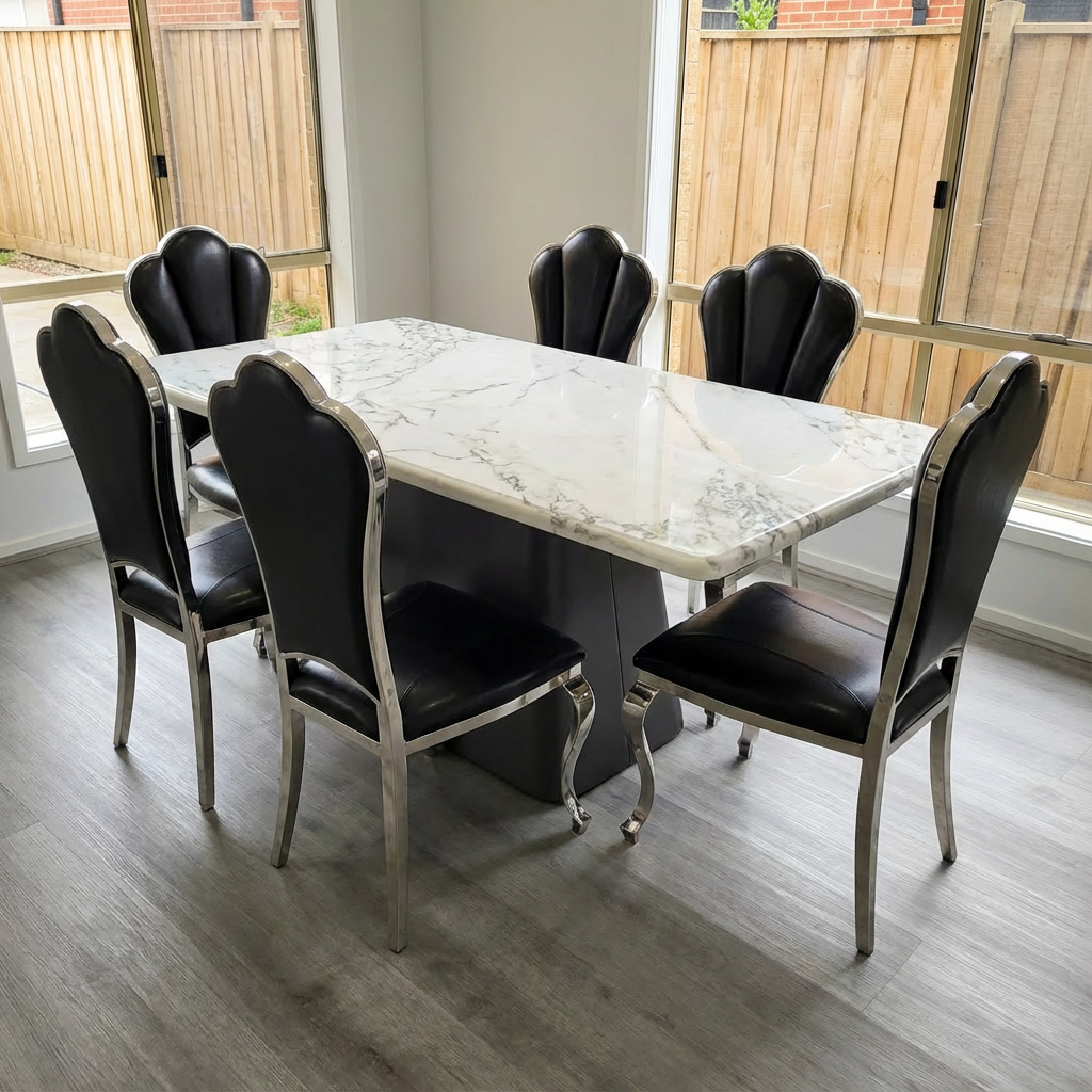 Dining table with marble top and black chairs in a room with large windows.