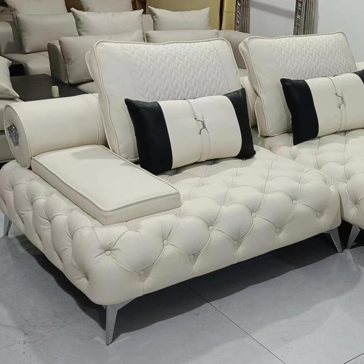 White tufted sofa with black pillows in a showroom setting