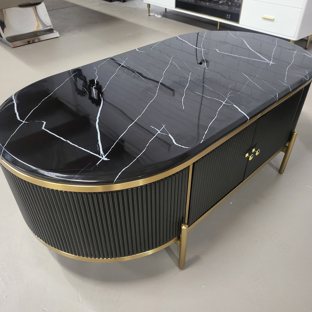 A black modern marble top coffee table with stainless steel frame and gold accents, featuring four drawers.