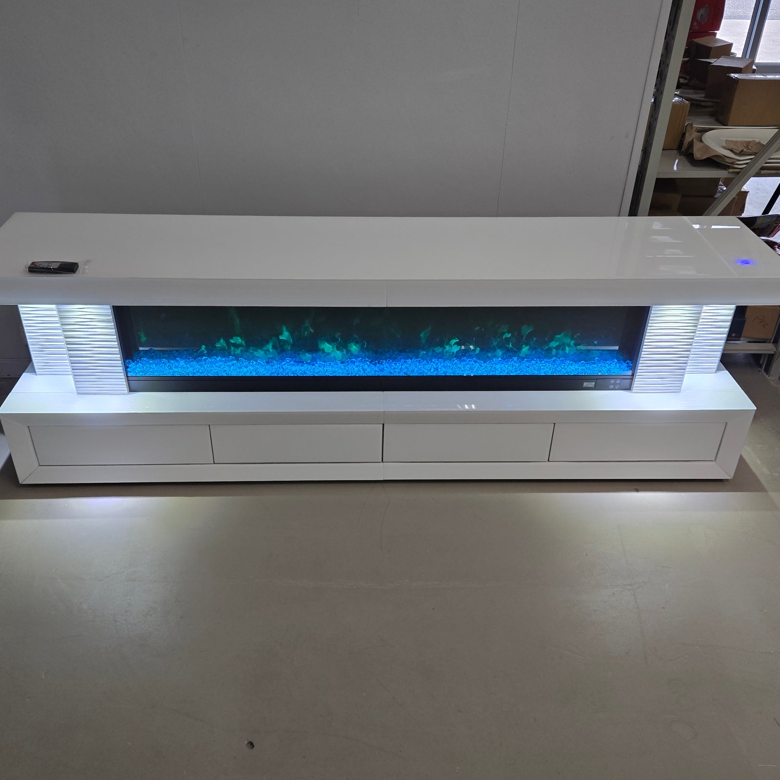 An Exclusive 4 Drawer White Glass and MDF TV Stand/Unit with a Stylish look. This Sleek Fireplace Reflector comes with 13 Colour Changes, Bluetooth Speakers, a Touch Screen, and a Remote for Seamless Operation