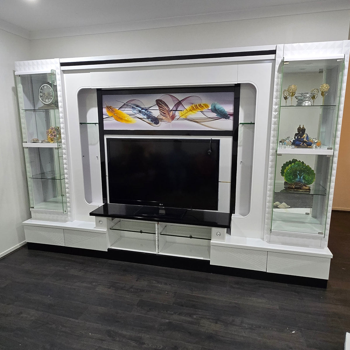 White entertainment console with glass panels and decorative items.