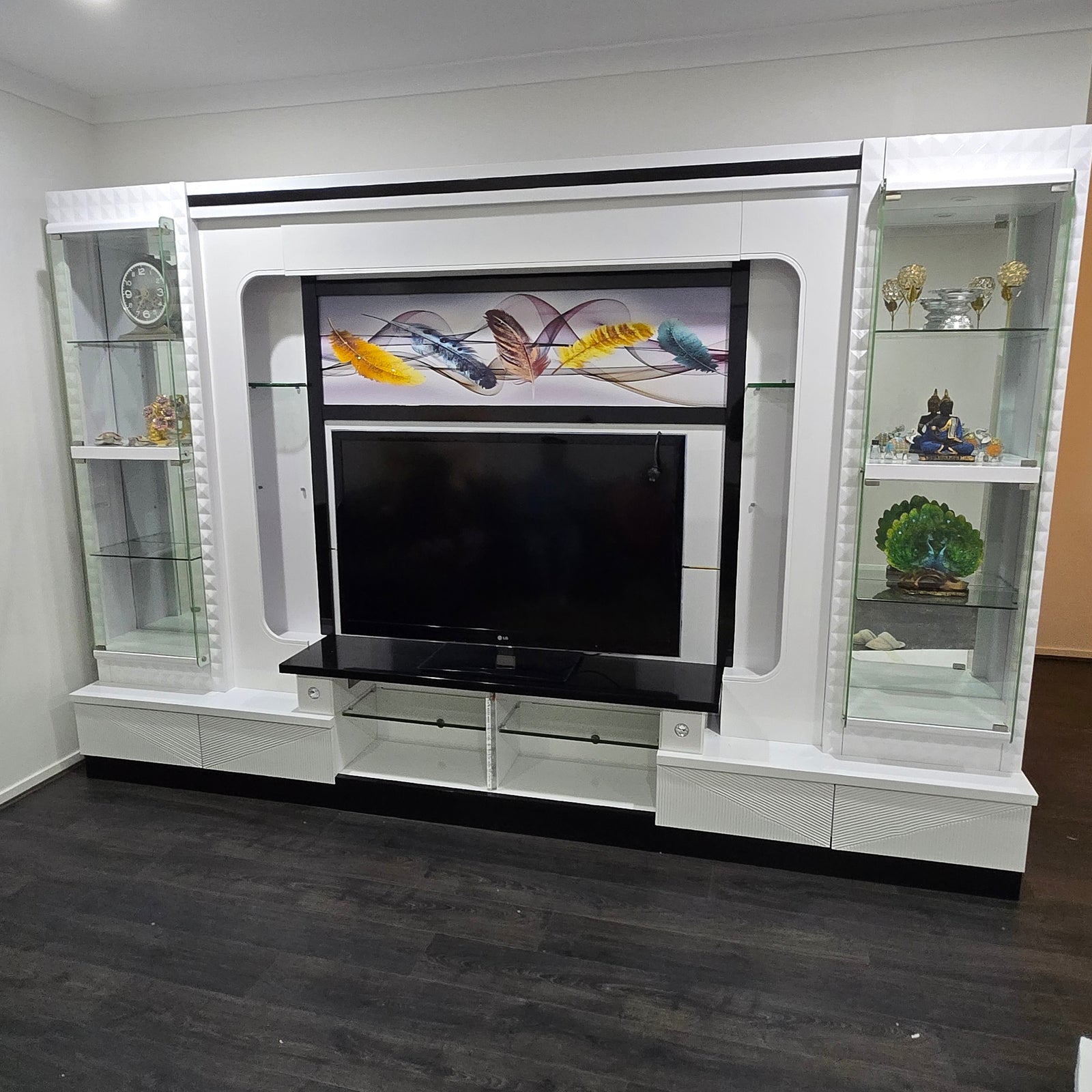 White entertainment console with glass panels and decorative items.