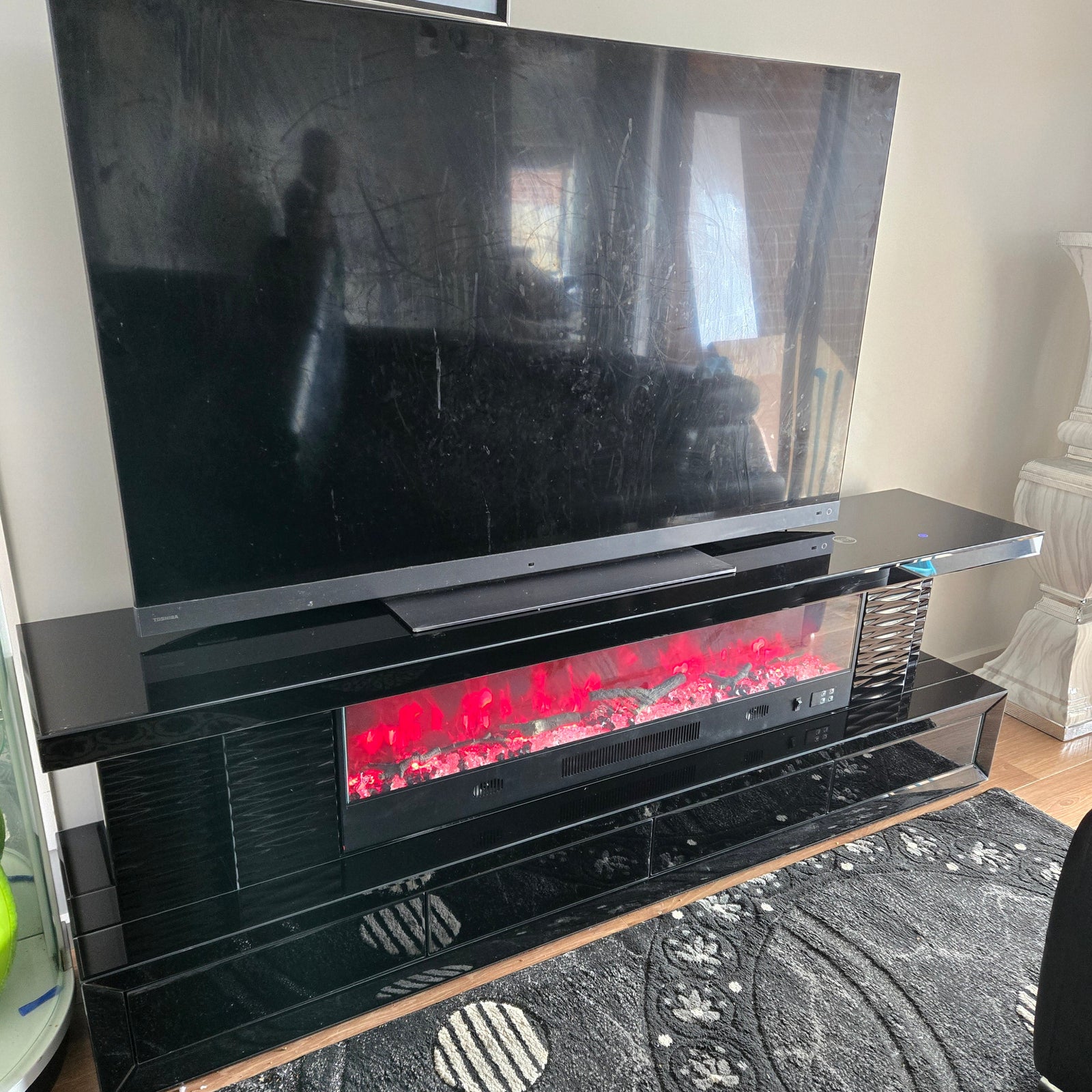 Open black electronic device on a surface with a patterned rug in the background
