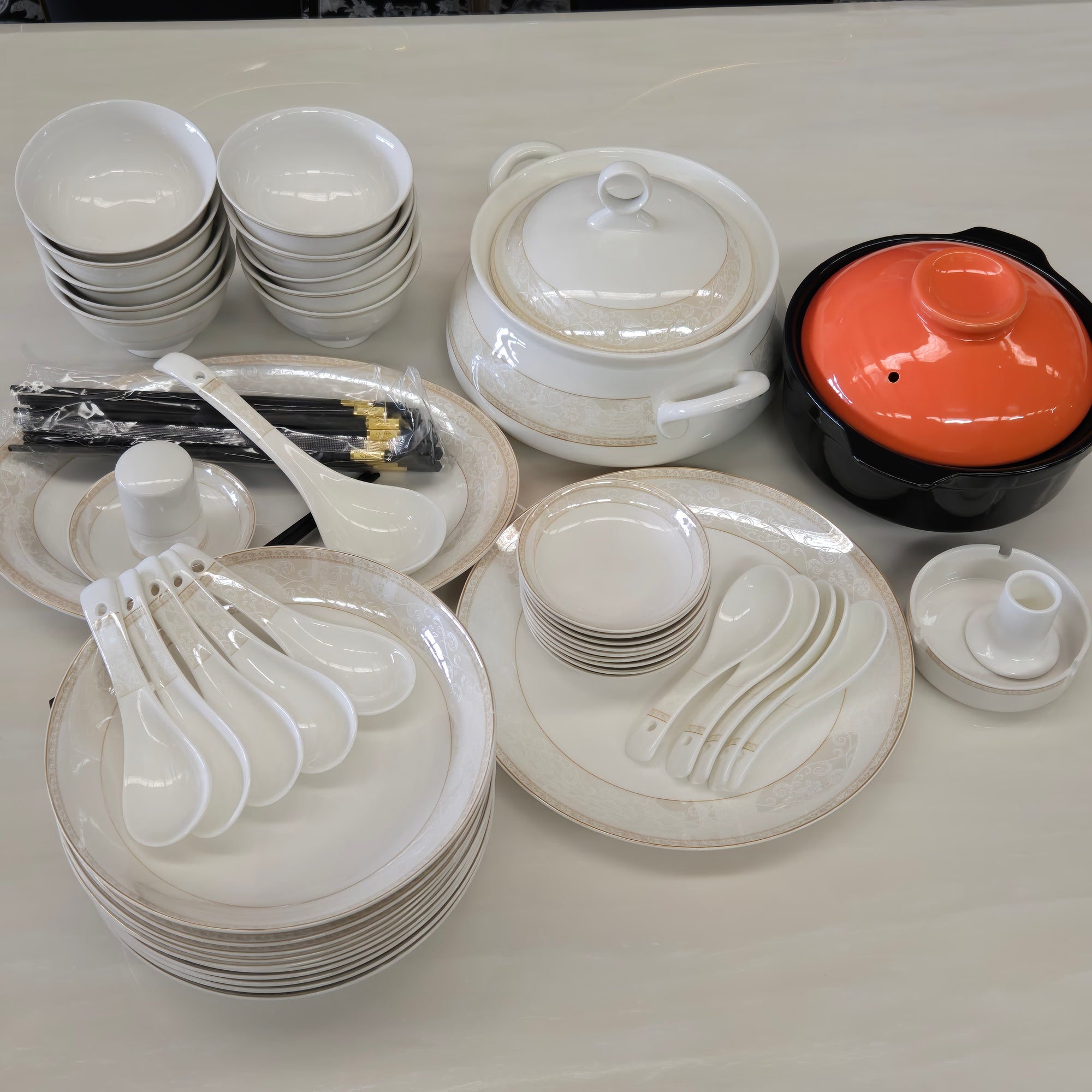 Collection of white ceramic dishes including bowls, plates, and cups on a light gray surface.