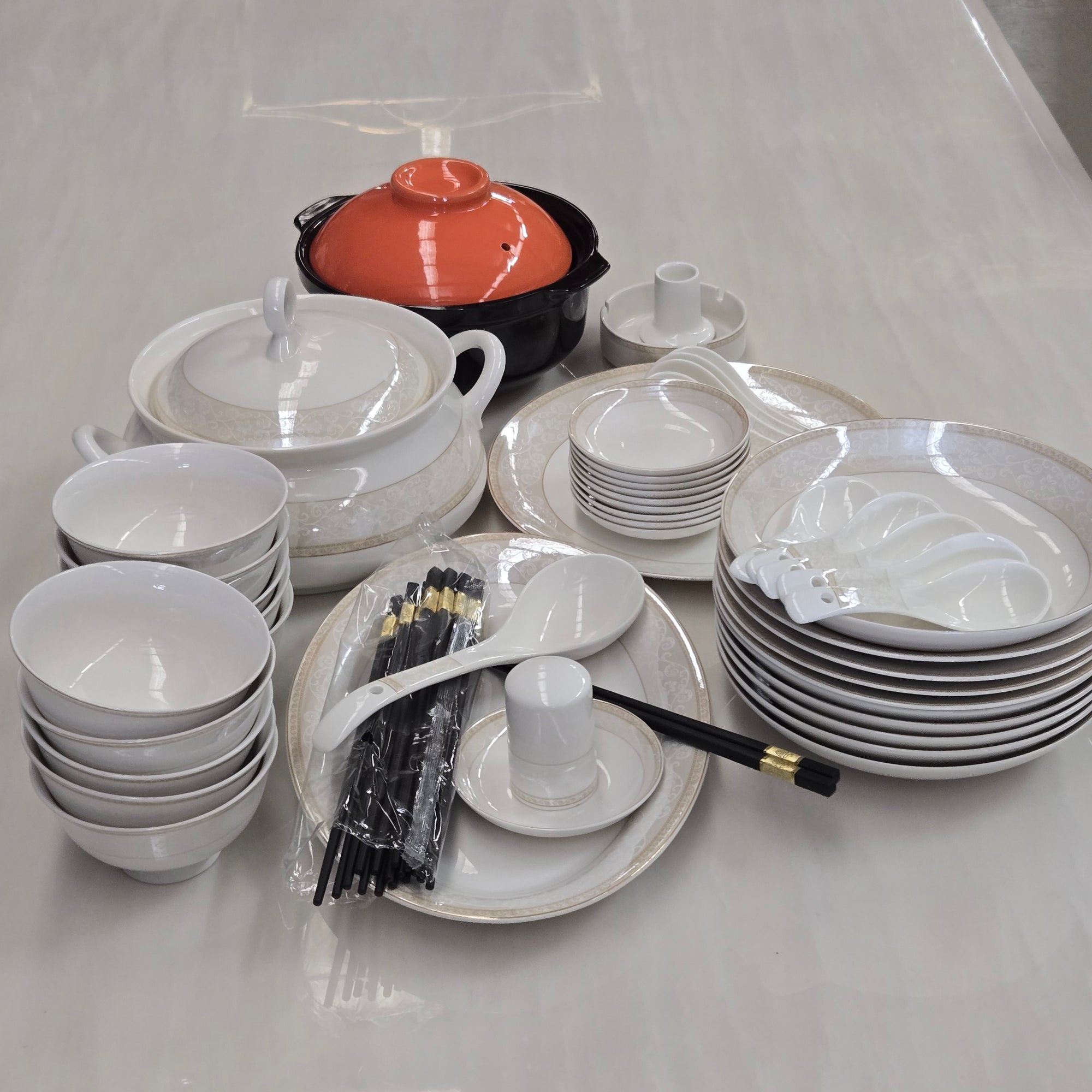Stacked white ceramic dishes with black tools on a light gray background