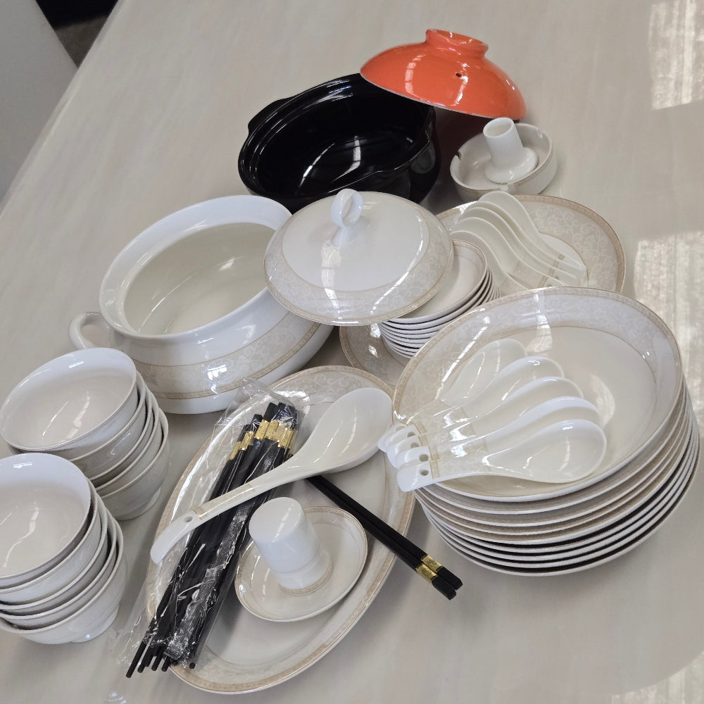 Pure Ceramic Stacked white dishes including bowls, plates, and cups on a light gray surface.