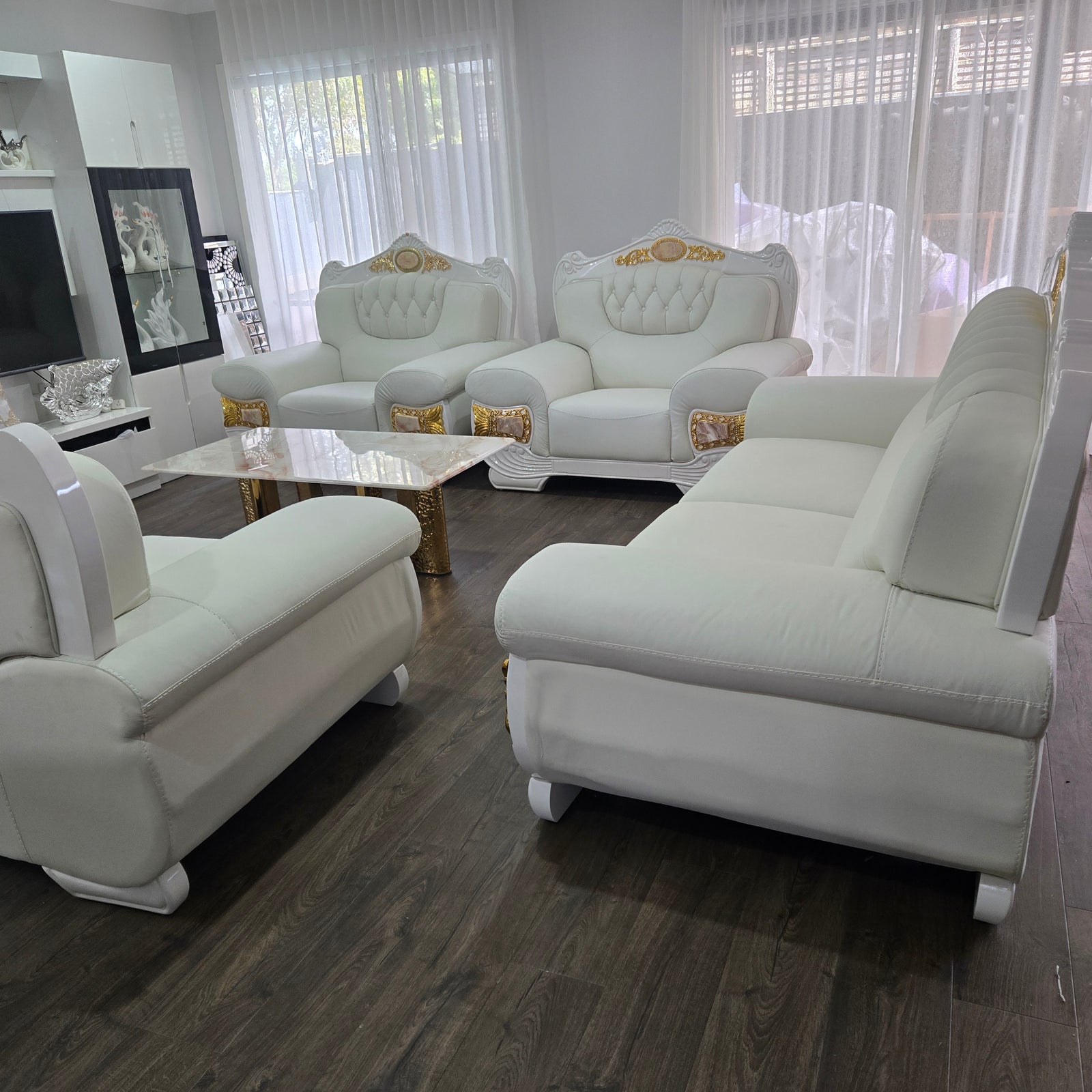 White leather sofa set in a living room with wooden floor and window blinds.
