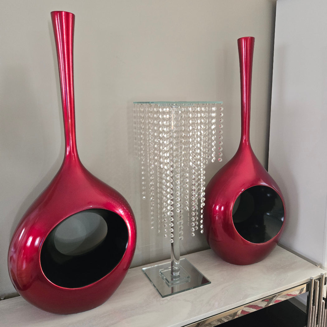 Two red ceramic pots with long handles on a light surface.