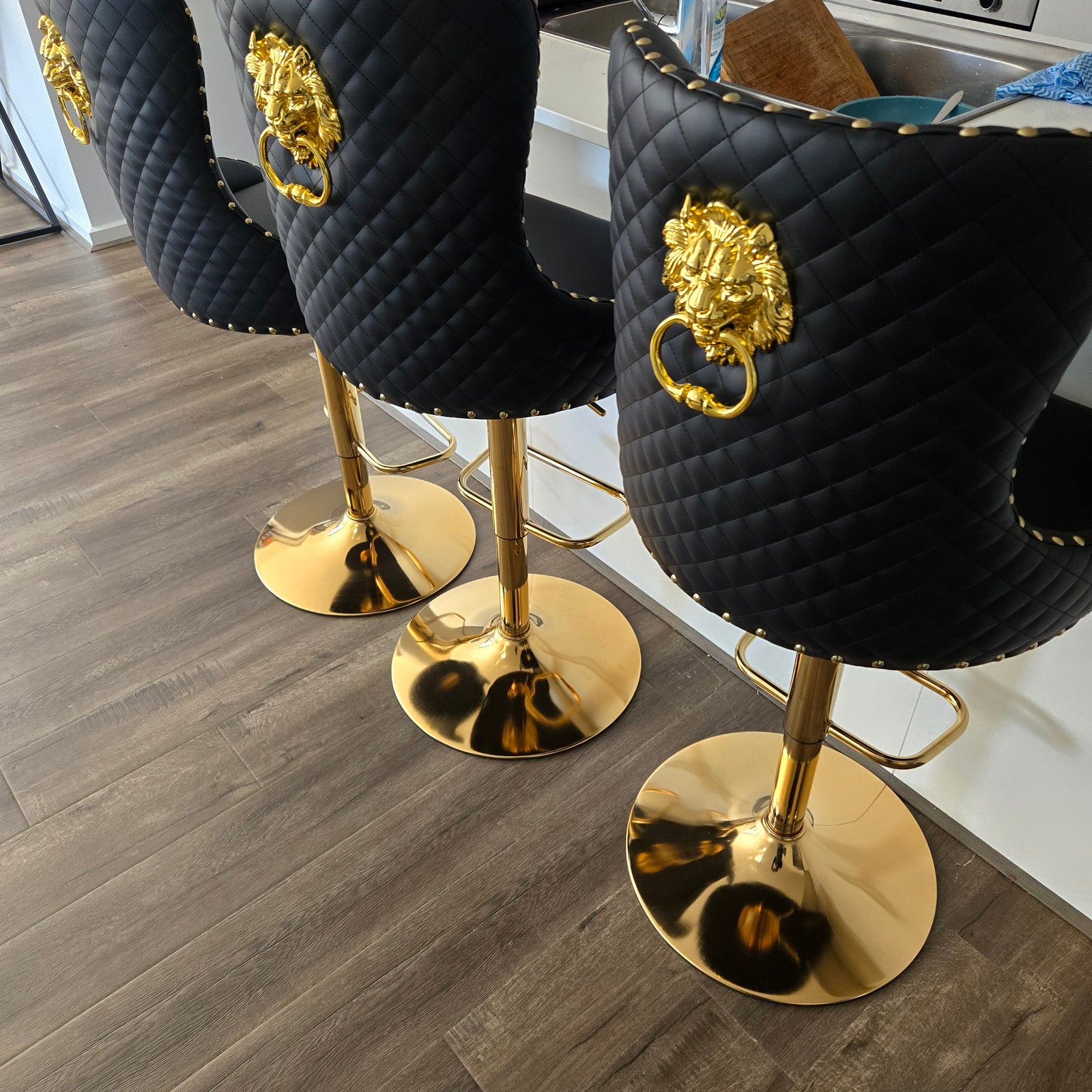 Black bar stools with gold legs on a wooden floor