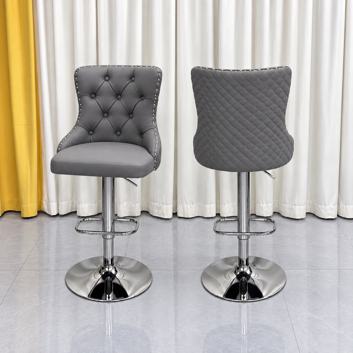 Grey tufted bar stool with silver stainless steel pedestal base and quilted backrest. 
