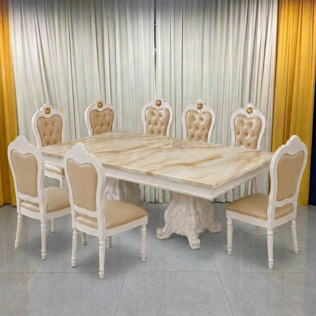 An 8-piece dining set featuring a rectangular table with a beige marble-patterned top and a carved white pedestal base, surrounded by six matching chairs with tufted cream upholstery and white frames.