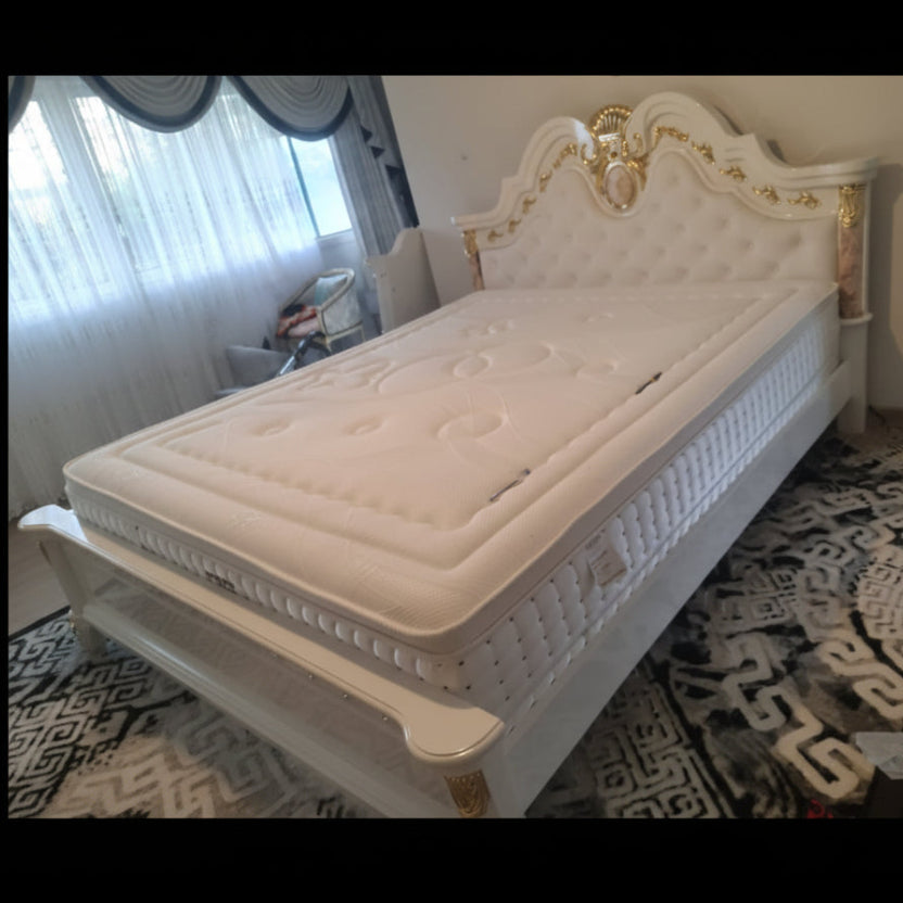 White bed with gold accents in a room setting