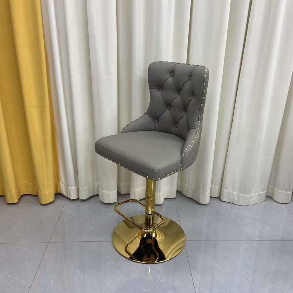 Grey Leather quilted bar stool with gold base and lion emblem against a white curtain background