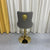 Grey Leather quilted bar stool with gold base and lion emblem against a white curtain background