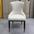 White upholstered chair with black legs against a geometric-patterned wall.