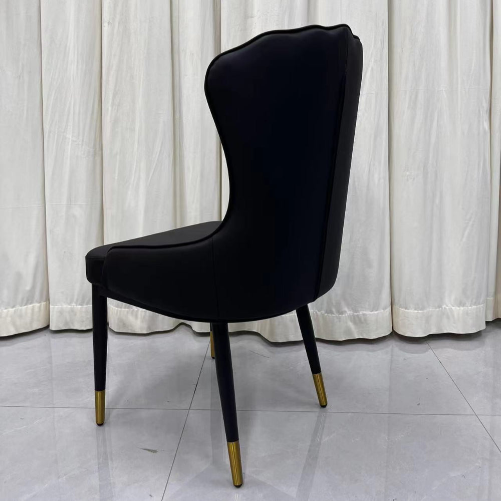 Black chair with gold legs against a white curtain background
