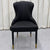 White upholstered chair with black legs against a geometric-patterned wall.