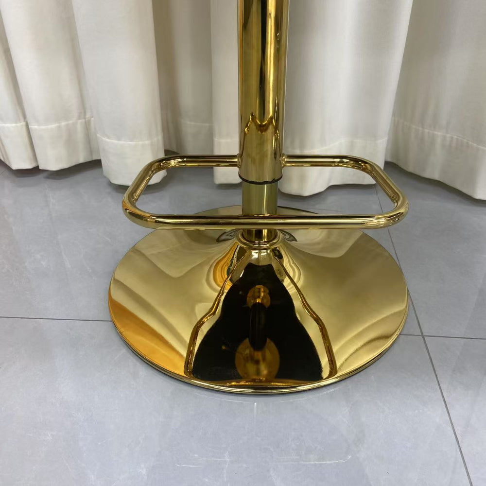 Gold bar stool on a tiled floor with white curtains in the background
