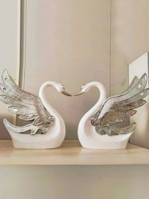 Decorative swan figurines with wings on a shelf.
