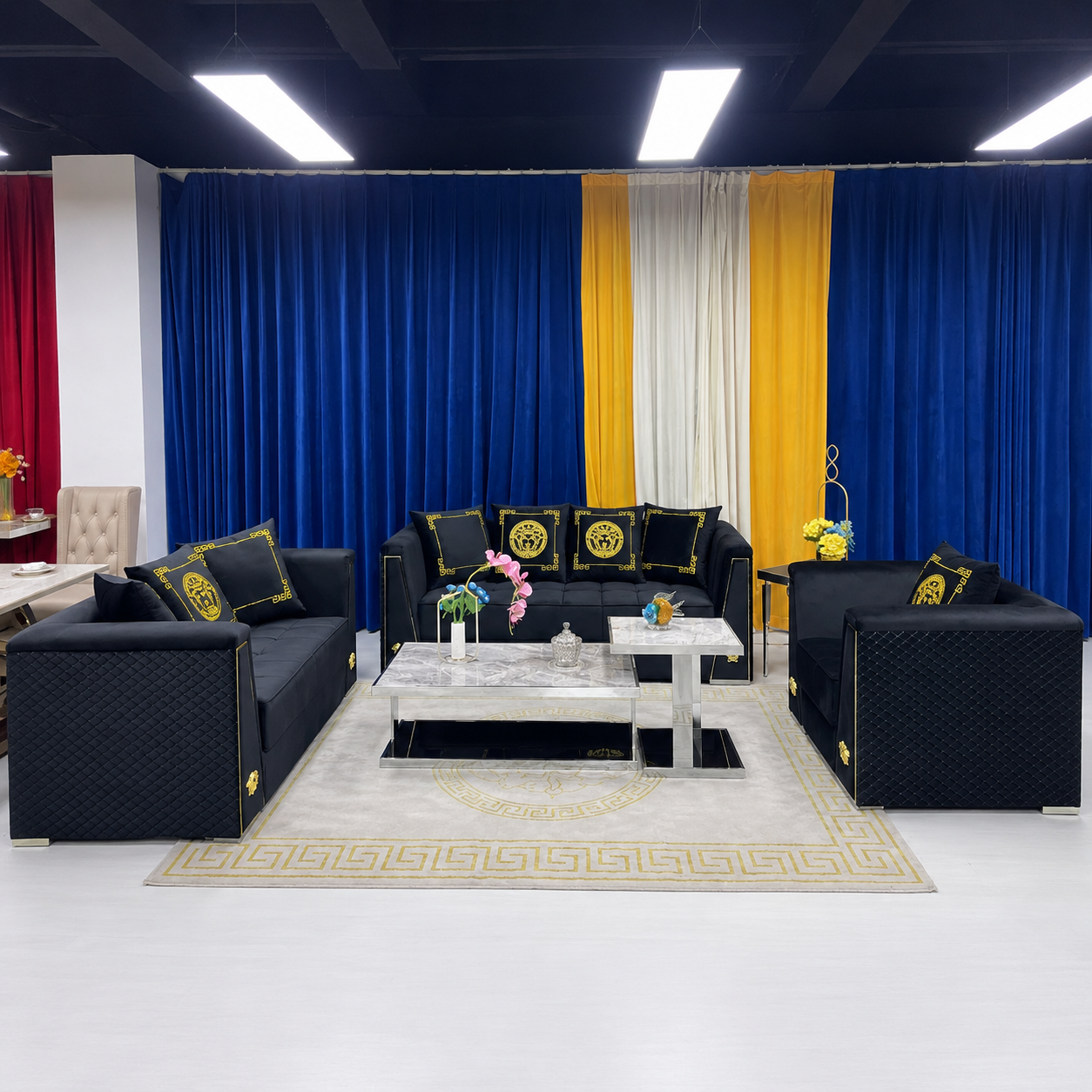 A luxury black woven sofa set with gold circular medallion pillows, arranged in a showroom with blue, white, and yellow curtains in the background.