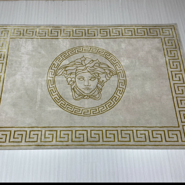 Decorative wall panel with a Greek key border and central emblem on a white wall.
