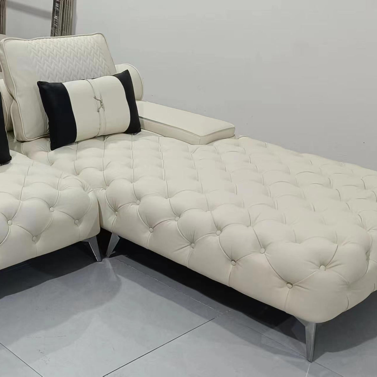 White sectional sofa with black and white pillows on a tiled floor.