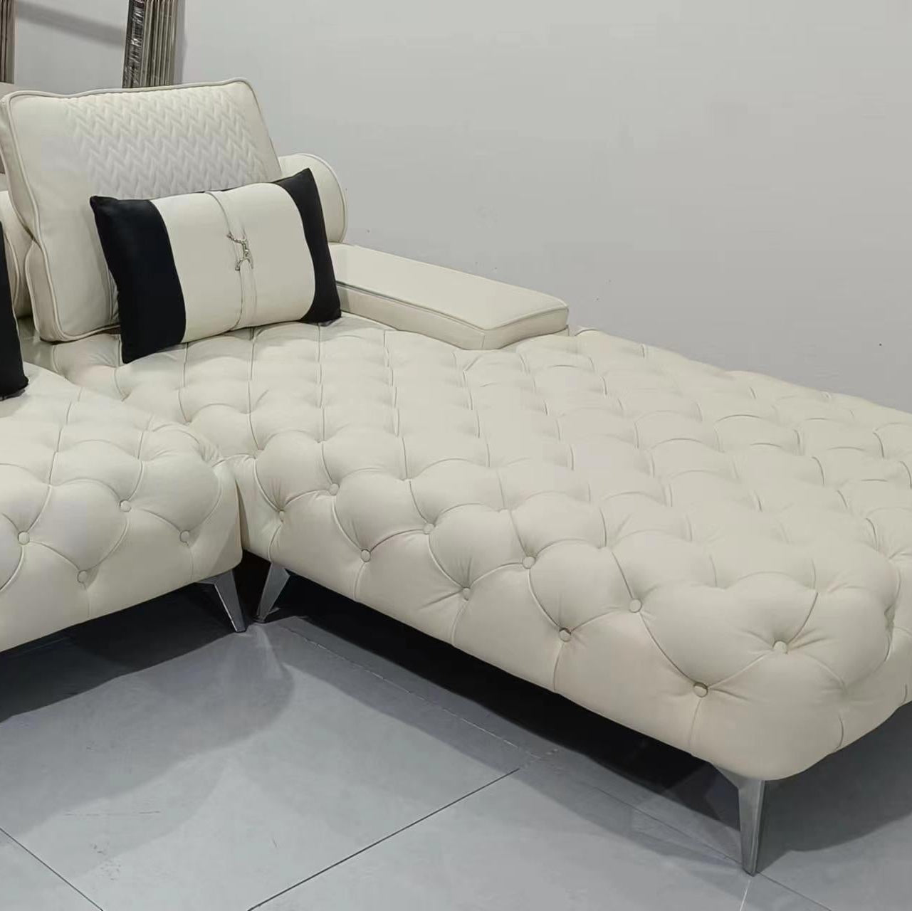 White sectional sofa with black and white pillows on a tiled floor.