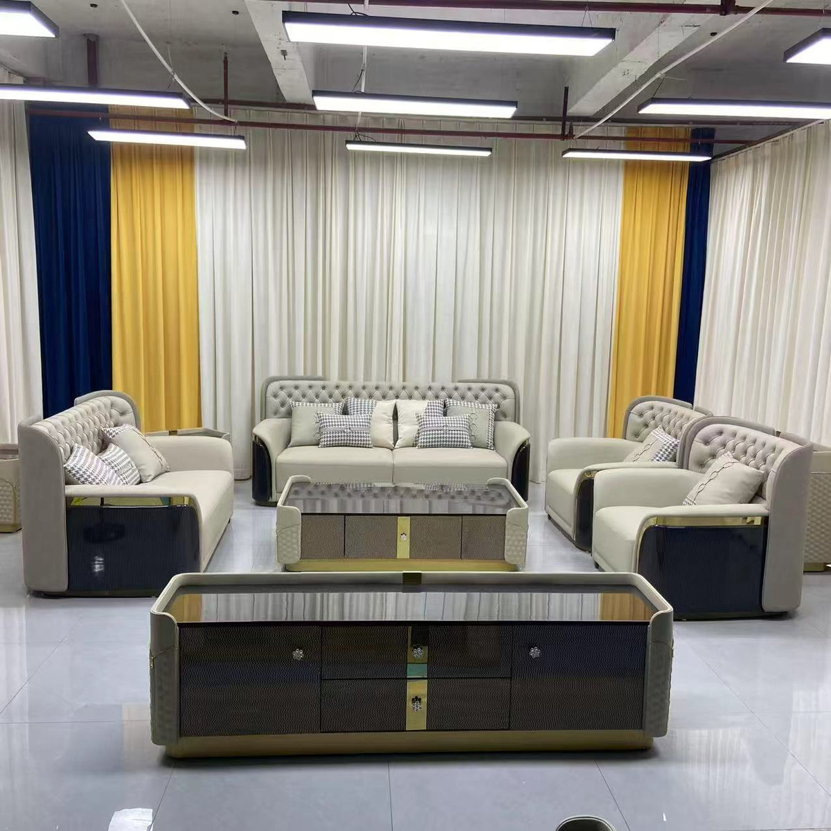 Modern living room setup with beige sofas, coffee table, and decorative pillows in a showroom.