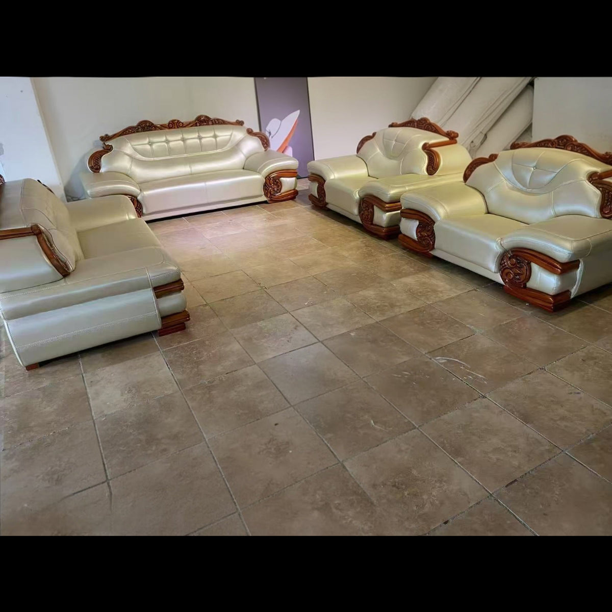 White leather sofa set with wooden accents on a tiled floor.
