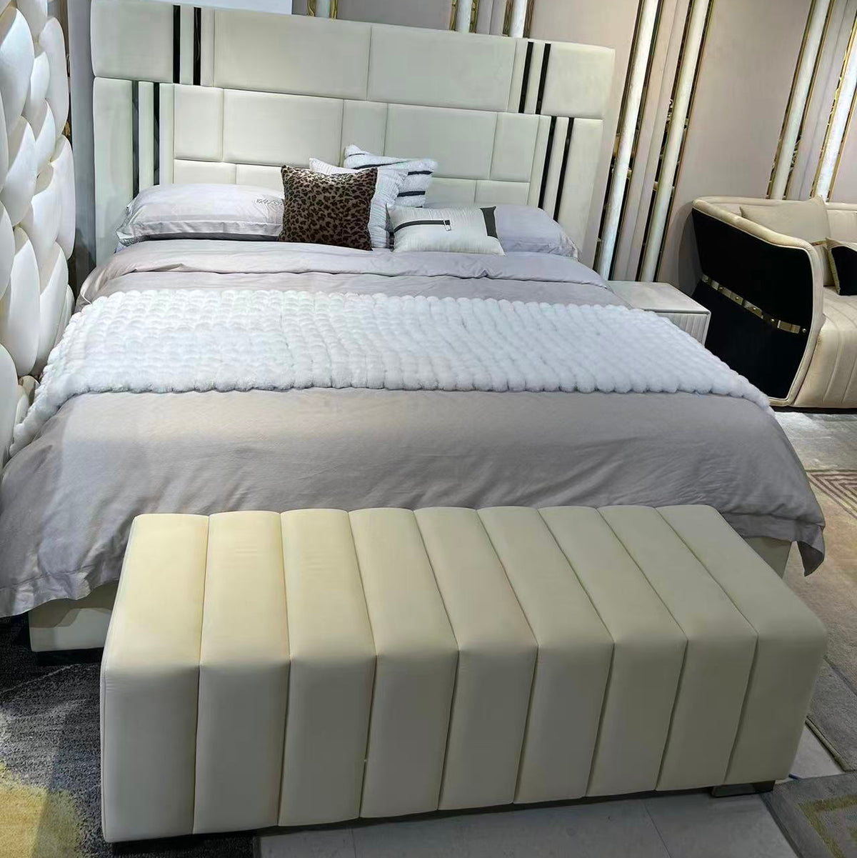 Modern bedroom with a bed and bench against a decorative wall.