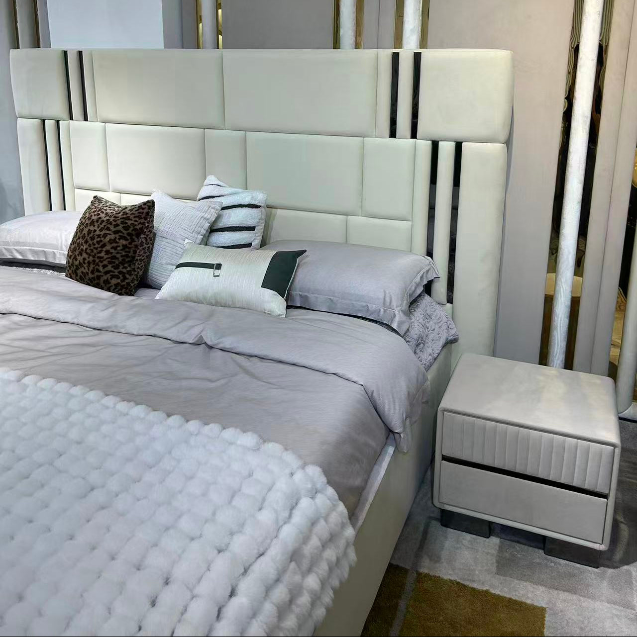 Modern bedroom setup with a bed and nightstand against a neutral wall.