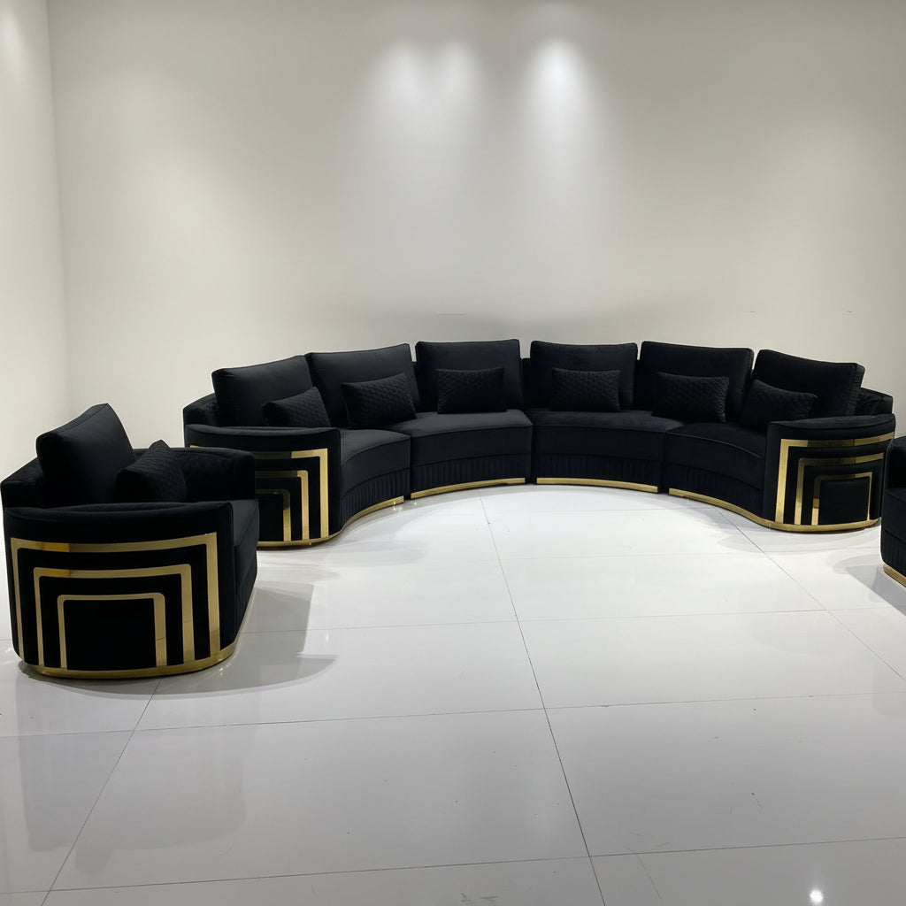 A curved modular sofa set with two matching armchairs, upholstered in taupe fabric with prominent gold geometric frame accents, set against a minimalist white wall and tiled floor.
