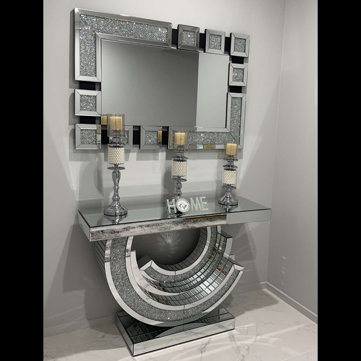 Decorative console table with mirror and candles in a room with gray walls and white floor.